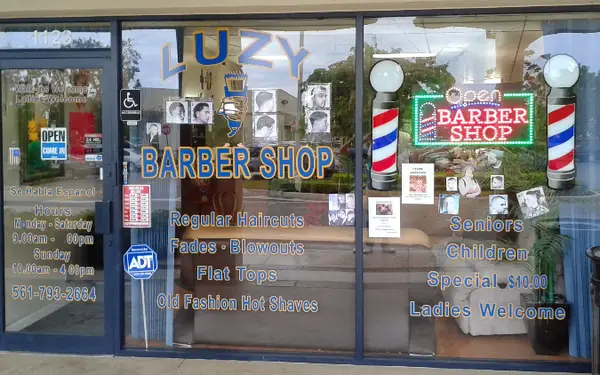 La vidriera de Luzy Barber Shop con letras azules y doradas y dos lámparas de poste de barbero
